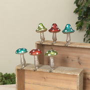 Colorful mushroom-shaped lights on a wooden surface with a natural background