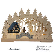 Landhaus Schwibbogen 699: wooden laser-cut silhouette with half-timbered house, forest trees, bridge, and figurines, illuminated.