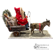 Donkey Cart Santa Candy Container with seated figure in red coat, wooden cart filled with greenery and logs, pulled by harnessed gray donkey on base.