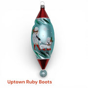 Step into vintage holiday charm with Uptown Ruby Boots. This German hand-blown ornament features a chic winter lady and her stylish pup—both sporting bold ruby-red boots—set against a shimmering aqua-blue twist silhouette. Glittering snowflakes and classic retro colors complete the playful, mid-century look.

Made in Germany • Designed by Timothy De Clue