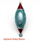 Step into vintage holiday charm with Uptown Ruby Boots. This German hand-blown ornament features a chic winter lady and her stylish pup—both sporting bold ruby-red boots—set against a shimmering aqua-blue twist silhouette. Glittering snowflakes and classic retro colors complete the playful, mid-century look.

Made in Germany • Designed by Timothy De Clue