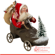Driving Shoe Crazy Santa in paper mache vehicle with snow-dusted tree, holding reins and gift sack.