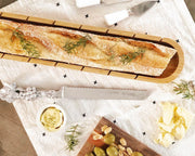 Baguette Board with Grape Bread Knife displayed with rosemary, butter, olives, and cheese on white linen.