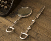 Bit Equestrian Letter Opener with silver horse bit handle displayed with magnifying glass on wooden surface