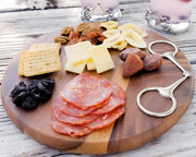 Cheese Board - Equestrian Bit styled with cured meats, cheeses, crackers, nuts, dried fruit, and decorative silver serving utensils on round wooden platter.