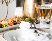 Deer Stoneware Napkin Ring on white plate with crackers, champagne glass, and bottle at table setting