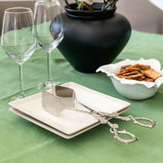 Acorn Oak Leaf Food Tongs in silver with decorative handles, displayed on white plates with wine glasses on green tablecloth.
