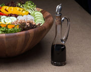 Cruet Bottle with Pewter Olive Head Cork Stopper next to wooden salad bowl with fresh vegetables